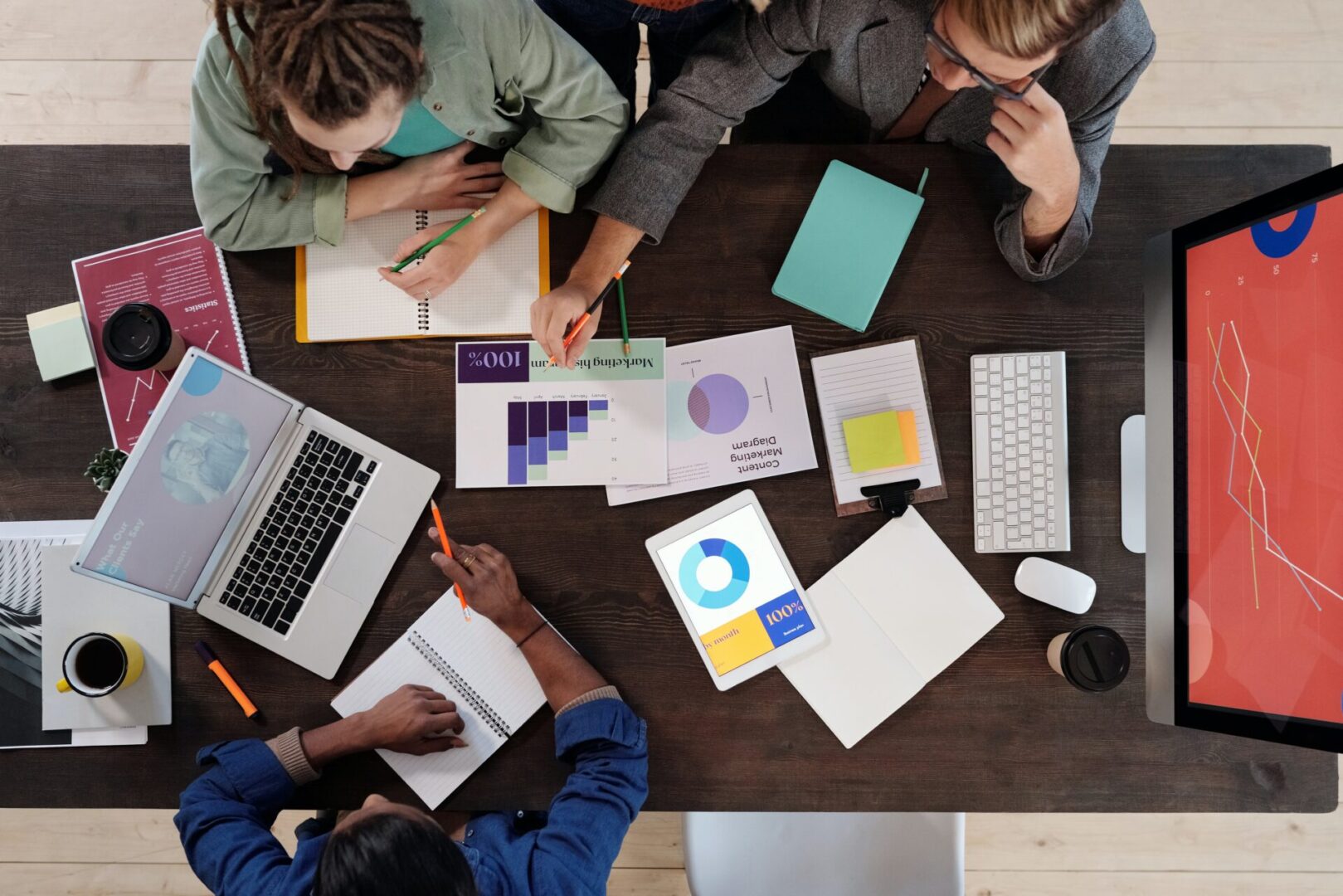 A group of people sitting around a table with papers and laptops.